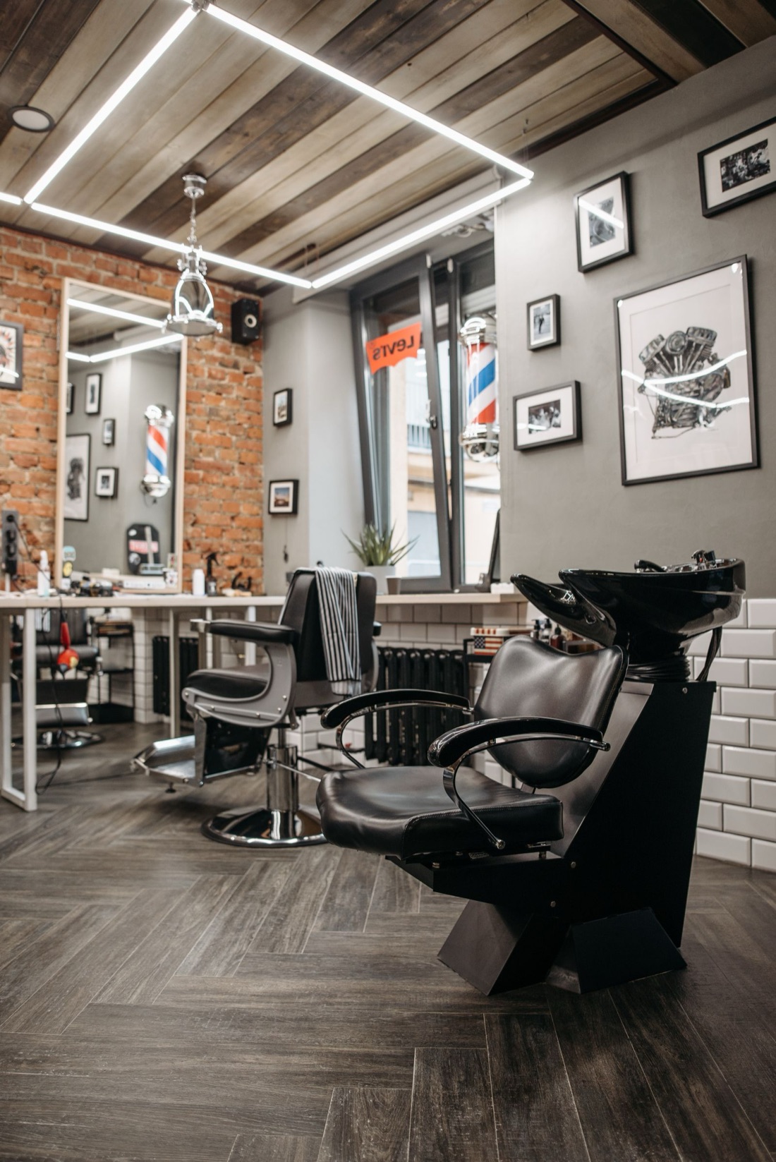 A modern barbershop interior with leather chairs and an exposed brick wall